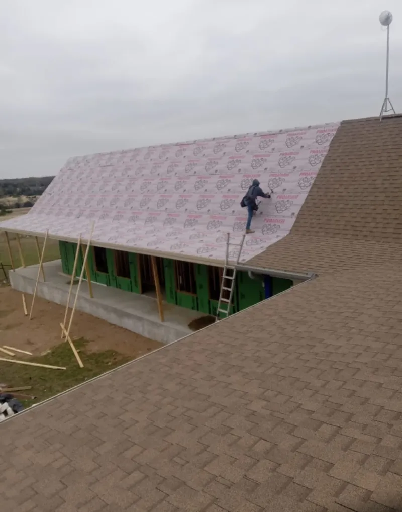 Worker preparing underlayment for a metal roof installation in Boone